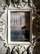 Load image into Gallery viewer, Framed artwork of a black bird over water with intricate white frame
